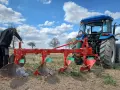 Rolnik przygotowuje pług do orania ziemi. Błękitne niebo z chmurami nad polem.