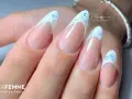 Unghie a mandorla con french manicure rivisitato: base nude e punta bianca con brillantini scintillanti, un tocco di french rosso con brillantini.