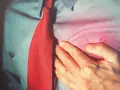 Mężczyzna w czerwonym krawacie trzyma się za serce, odczuwając ból. Może to być sygnał, by zadbać o swoje concor cor.