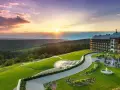 Hotel Arłamów z basenem i tarasem, otoczony zielonymi wzgórzami o zachodzie słońca. Ile pokoi ma hotel Arłamów? Tego nie widać, ale jest ich wiele!