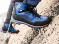 Close-up of a blue and black hiking boot with orange accents, gripping a rocky surface.
