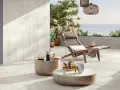 Terrasse en travertin avec mobilier de jardin et vue sur la mer.