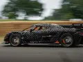 Czarny, pikselowy hypercar z pomarańczowymi akcentami pędzi po torze, tworząc wrażenie ruchu.