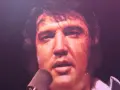 Elvis Presley, sichtlich erschöpft, singt in ein Mikrofon. Ein Moment, der an seinen elvis presley last concert erinnert.