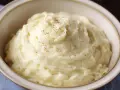Un cremoso puré de patatas, espolvoreado con pimienta negra y roja, servido en un cuenco.