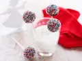 Söta cake pops med pepparkakssmak, dekorerade med färgglada strössel. En vit ängel i bakgrunden.