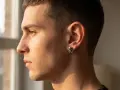 Zbliżenie na profil mężczyzny z kolczykiem w kształcie czaszki z piszczelami w lewym uchu.