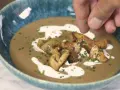 Crema de champiñones servida en un cuenco azul, decorada con champiñones salteados, picatostes y un chorrito de nata.