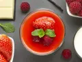Delizioso dessert con coulis di fragole, fragole fresche, lamponi, menta, cioccolato bianco e un baccello di vaniglia.