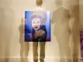 Retrato pop de la Reina Isabel II, obra de el artista anonimo, rodeado por siluetas fantasmales de visitantes en una galería.