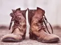 Stivali in pelle marrone consumati, con lacci sciolti. Perfetti per chi cerca un modo per ammorbidire il tallone delle scarpe.