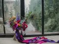 Bogaty bukiet z pawimi piórami i fioletowymi wstążkami. Każdy kwiat ma swoje znaczenie, tworząc kompozycję pełną symboliki.
