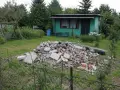 Kupa gruzu na działce ROD. Czy komornik może zająć działkę ROD? W tle zielona altanka, huśtawka i drzewa.