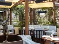Terrazza lussuosa con statue e piante, tavoli apparecchiati per un'esperienza culinaria al **Wilde Milano**.