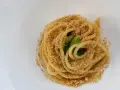Spaghetti conditi con aglio, olio e peperoncino, cosparsi di pangrattato croccante e qualche foglia verde.