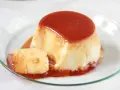 Delicioso flan de huevo en flanera con tapa, bañado en caramelo líquido y servido en un plato de cristal.