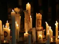 Viele Kerzen brennen in der Dunkelheit, einige mit Bildern und Kreuzen verziert. Ein stimmungsvolles Bild, das an Maria Lichtmess erinnert.