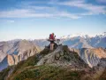 Escursionista con cane su cresta rocciosa, sfondo di montagne innevate nei GR10 Pirenei.