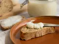Ein Glas mit selbstgemachtem Schmalz steht bereit. Eine Scheibe Brot wird gerade mit dem Schmalz bestrichen, ein Genuss für jeden, der Schmalz selber machen möchte.