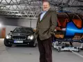 Jarosław Gołębiewski Tago w hangarze obok luksusowego samochodu i helikoptera.