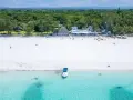 Idealne kenia wakacje: biała plaża, turkusowa woda, łódź i tropikalna roślinność.