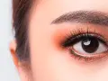 Occhi luminosi con un tocco di trucco coreano: ombretto pesca, eyeliner sottile e ciglia lunghe e folte.