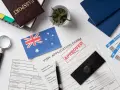 Paszport, formularz wizowy z pieczątką "APPROVED", flaga Australii, bilety lotnicze.
