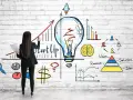 Mujer dibuja un gráfico de crecimiento y una bombilla, simbolizando cómo capitalizar el paro con una idea de startup.