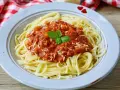 Teller mit Spaghetti Bolognese, bestreut mit Parmesan und garniert mit Basilikum. Perfekt für schnelle Bolognese für Kinder.