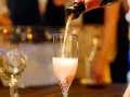 Nalewanie musującego **cava wino** do kieliszka. W tle widać inne kieliszki i rozmyte światła, sugerujące uroczystą atmosferę.