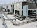 Unidades de aire acondicionado industriales en una azotea, con tuberías de ventilación y aire acondicionado (HVAC) conectadas.