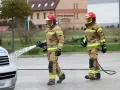Strażacy w akcji, jeden z węża wodnego. Zastanawiasz się, ile zarabia strażak? To praca pełna wyzwań.