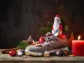 Ein Schuh gefüllt mit Leckereien, daneben ein Schokoladen-Nikolaus, Tannenzweige und eine brennende Kerze.