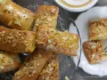 Omas Apfeltaschen Rezept: goldbraune, glasierte Gebäckstücke mit Mandelblättchen, serviert auf einem Glasständer und einem Teller, daneben eine Tasse Kaffee.