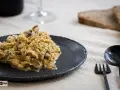 Delicioso revuelto de setas servido en plato oscuro, acompañado de pan y cubiertos.