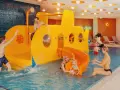 Rodzina bawi się w hotelu z aquaparkiem dla dzieci w górach. Żółta łódź podwodna ze zjeżdżalnią to centrum wodnych atrakcji.