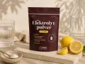 En påse elektrolytpulver med citronsmak, bredvid färska citroner, ett glas vatten och en skål med pulver. Selen finns i för att återställa vätskebalansen.
