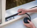Hände legen eine neue Fensterdichtung an, um Zugluft zu vermeiden.