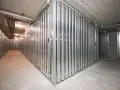 Korytarz z rzędami metalowych przegród tworzących komórki lokatorskie.