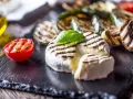 Pyszny camembert z grilla, z rumianymi paskami, podany z grillowanymi warzywami i pomidorkiem.