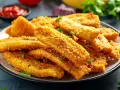 Bastoncini croccanti di zucchine in friggitrice ad aria, dorati e saporiti, guarniti con prezzemolo fresco.