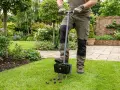 Gartenarbeit nach dem Winter: Ein Mann belüftet den Rasen mit einem speziellen Werkzeug, um ihn für die neue Saison vorzubereiten.
