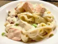 Cremige Nudeln mit Lachs, Erbsen und Dill in einer weißen Schüssel.