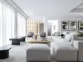 Elegante salón pintado en gris, con sofás blancos, sillones grises y arte abstracto.