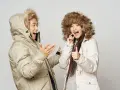 Pareja feliz con abrigos de invierno, ¡el mejor abrigo para el frío! Ella da pulgar arriba, él gesticula.