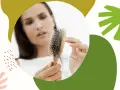 Zmartwiona kobieta trzyma szczotkę z garścią włosów. Szuka babcinych sposobów na wypadanie włosów.