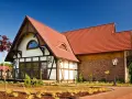 Elegancki dom z charakterystycznym dachem pokrytym czerwoną dachówką karpiówką, otoczony zadbanym ogrodem.