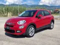 Fiat 500X rossa parcheggiata all'aperto, con montagne sullo sfondo. La pressione gomme è ottimale per ogni viaggio.