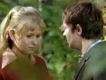 Irena Hrehorowicz w otoczeniu zieleni, spogląda w dół, rozmawiając z mężczyzną.