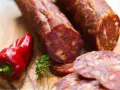 Kawałki pikantnego chorizo, czerwona papryczka i natka pietruszki na desce. Chorizo co to? To aromatyczna kiełbasa!
